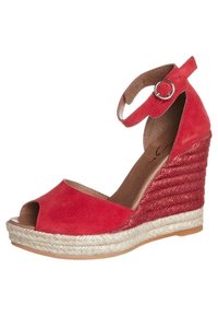 Sandale compensée en suède rouge avec un bout découvert, une sangle à la cheville et des détails en jute tressé sur le talon. Présente un dessus lisse et texturé.