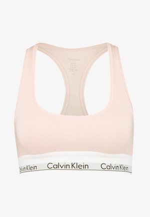 Calvin Klein sportbeha in lichtroze. Heeft een zachte stof, racerback-ontwerp en een witte band met zwarte logo-tekst aan de onderkant.