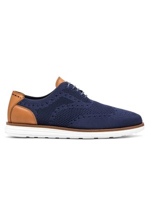 Zapatos de malla azul marino con acentos de cuero marrón claro y suela de goma blanca. Presentan detalles perforados y un diseño de puntera redonda.