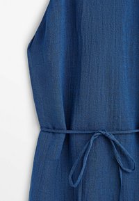 Robe en lin bleu avec une surface texturée, dotée d'une ceinture à nouer à la taille pour un ajustement et d'un design simple sans manches.