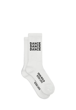 Witte enkelsokken met "DANCE DANCE DANCE" verticaal geprint nabij de bovenkant en "FROM BERLIN WITH LOVE" op de voet in zwarte letters.