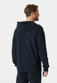 Felpa con cappuccio di colore blu navale, dall'aspetto morbido, con cappuccio regolabile, maniche lunghe e vestibilità rilassata. Nessun logo o motivo visibile.