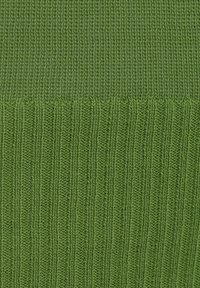Tessuto lavorato a maglia verde con due texture: una sezione superiore liscia e una sezione inferiore a coste, entrambe in una tonalità di verde uniforme.
