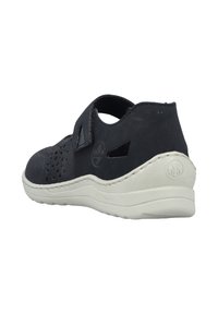 Schwarze Wildledersandalen mit Ausschnitten, verstellbarem Riemen und weißer Sohle. Mit niedrigem Absatz und geprägtem Logo auf der Rückseite.