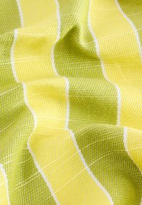 Textil mit einer wellenförmigen Struktur, die abwechselnd gelbe und grüne Streifen aufweist, getrennt durch dünne weiße Linien und ein Gittermuster zeigt.