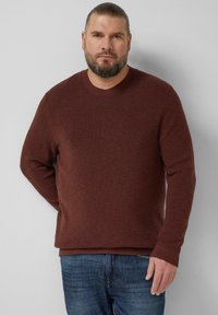 Brązowy, prążkowany sweter z dzianiny z okrągłym dekoltem, długimi rękawami i luźnym krojem, zestawiony z niebieskimi jeansami. Prosty design, fakturowana tkanina.