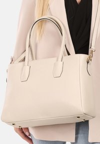 Beige leren handtas met twee bovenhandvatten, rechthoekige vorm, gestructureerde afwerking, subtiele zwarte stiksels en gouden hardware accenten.