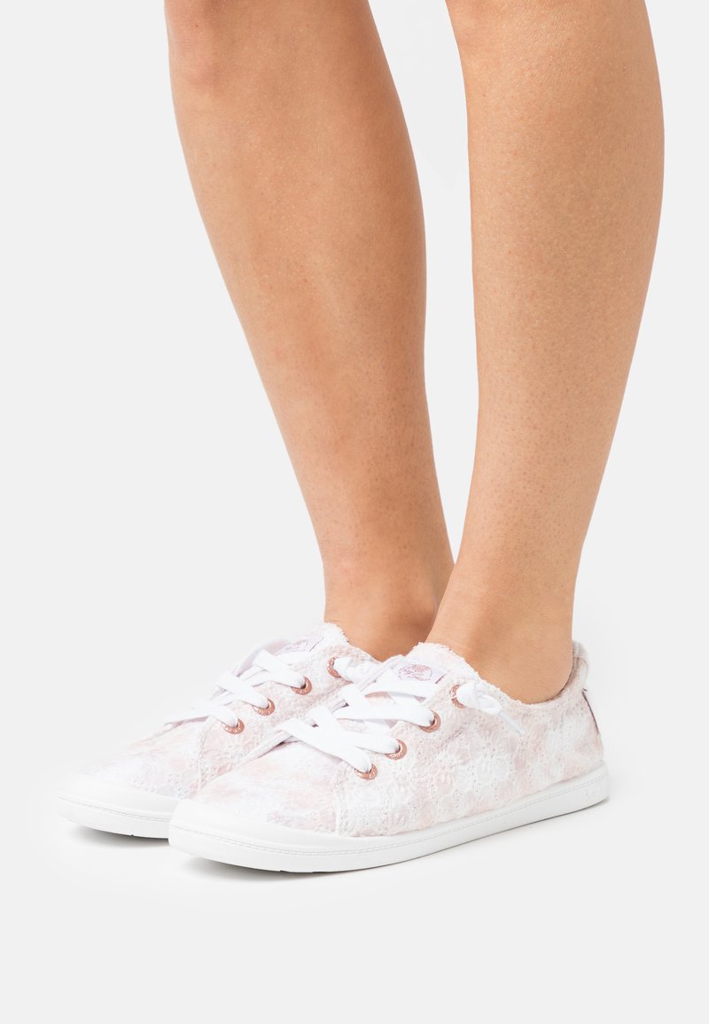 Lisse-sko med et lett rosa teksturert stoffoverdel, hvit såle og roségull eyelets. Myk fôr og rund tådesignet.