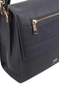 Navyblauwe leren handtas met een gestructureerd design, goudkleurige hardware en een ritsvak aan de voorkant. Textuur oppervlak met logo detail.