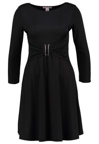 Robe noire à manches longues avec un décolleté rond, taille ajustée avec une boucle argentée et jupe évasée.