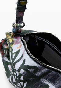 Handtasche mit Blumenmuster, strukturierter Oberfläche, Reißverschluss und einem bunten Riemen mit einem Metallschlaufen-Detail. Innenraum ist schwarz.