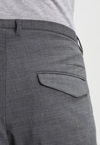 Grå texturerade byxor med en platt bakficka, skräddarsydd passform och en ren midja, lämpliga för formella eller avslappnade tillfällen.