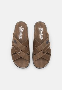 Braune Slipper-Sandalen aus strukturiertem Material, mit diagonalen Riemen und kontrastierender Naht. Logo auf den Innensohlen gedruckt.