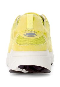 Geel sportieve schoen met een gestructureerde suède en mesh bovenkant, een gevoerde kraag en een dikke witte zool met een zwart rubberen profiel.