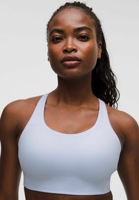Sujeta de deporte azul claro con una textura suave, tirantes anchos y un escote redondeado, diseñada para la comodidad y flexibilidad en la ropa deportiva.