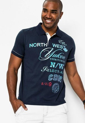 Polo shirt navy in cotone, con dettagli bianchi e varie scritte in turchese, rosso e bianco. Maniche corte e colletto.