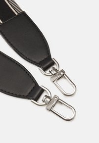 Sangle en cuir noir avec des clips en métal argenté, d'une texture lisse et d'un design élégant. Comprend des détails cousus le long des bords.