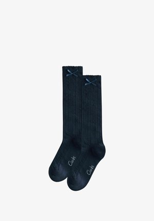 Paar schwarze gerippte knielange Socken mit kleinen schwarzen Schleifen oben und "Clarks"-Aufdruck nahe den Zehen.