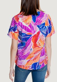 Top a maniche corte in colori vivaci con un motivo a foglia. Realizzato in tessuto leggero con una morbida texture. Orlo arrotondato e vestibilità rilassata.