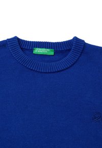 Modrý pletený svetr s ribbed kulatým výstřihem, měkkou texturou a malým logem na přední straně. Na štítku je napsáno "United Colors of Benetton."