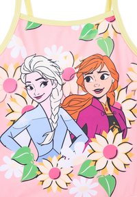 Zwemkleding met cartoonontwerpen van twee vrouwelijke personages tegen een roze achtergrond, versierd met grote witte en gele madeliefjes en groene bladeren.