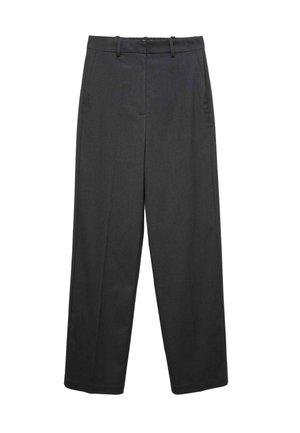 Femme portant un pull gris, un pantalon large taille haute noir, des mocassins noirs, et un sac à bandoulière marron, debout les mains dans les poches.