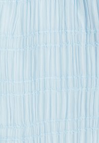 Helehallikas tekstuuriga kangas, millel on vertikaalsed voldid ja horisontaalsed volangiga ribad, luues pehme kihilise välimuse.