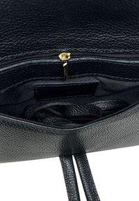 Wnętrze czarnej skórzanej torby na ramię o teksturowanym wykończeniu, z zamknięciem na zamek błyskawiczny i czarną tkaniną podszewkową. Zawiera regulowane skórzane paski.