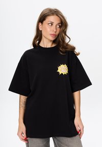 Czarna, oversize koszulka z bawełny z krótkimi rękawami. Posiada żółty nadruk z napisem "Lucky You" w wyrazistym, stylu pop-art.