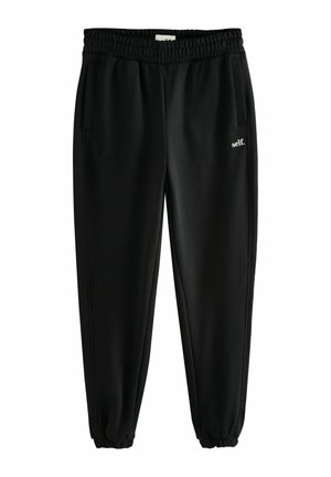 Zwarte trainingsbroek met een elastische tailleband, zijzakken en taps toelopende boorden. Bevat witte tekst "self." op het linkerbeen. Gladde textuur.