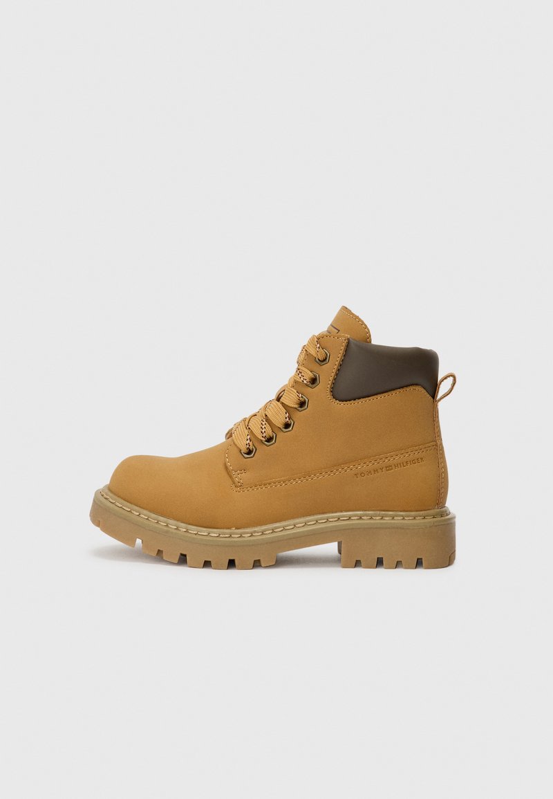 Botte de randonnée tan avec des accents en cuir brun, design à lacets, col rembourré et semelle en caoutchouc robuste avec un profond relief pour une meilleure traction.