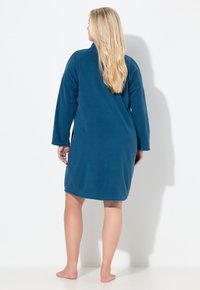 Blå fleece-kåbe med lange ærmer, knælangt design, blød tekstur og minimalistisk stil, der viser en glat, jævn overflade.