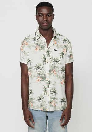 Short-sleeve button-up shirt in light beige with green palm trees and pink flowers. Features a chest pocket and brown buttons. Casual design.