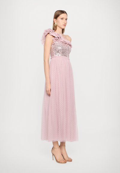 Einseitiges rosafarbenes Abendkleid mit einem mit Pailletten besetzten Oberteil und Rüschendetails aus Tüll, fließendem Rock mit Punkten, ergänzt durch nudefarbene High Heels.