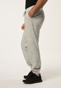 Grå, strukturerede sweatpants med snøre i taljen og sidelommer, design med tapered ben. Båret sammen med sorte træningssko.