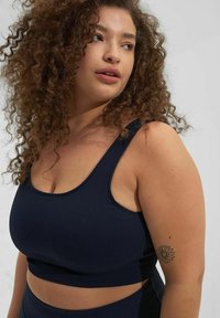 Marineblå ribbad sport crop top med tjocka remmar och en figurnära design, med en medellång skärning och en sidokutt detalj.