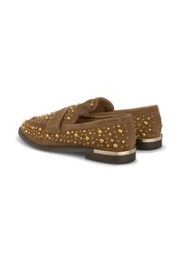 Bruine suède instappers met gouden metalen studs, een platte rubbere zool en een soepele kraag. Accenten aan de zijkanten voegen textuur en detail toe.