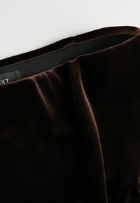 Ingrandimento di un tessuto in velluto nero con dettagli di cucitura e fascia elastica sulla vita di un indumento.
