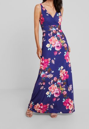 Robe maxi en bleu marine avec un motif floral. Dotée d'un décolleté en V, d'un design sans manches et d'une taille cintrée. Fabriquée en tissu extensible et lisse.