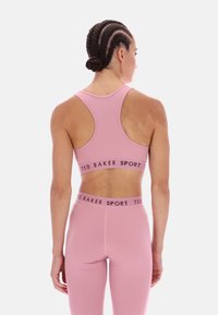 Rózsaszín sportmelltartó és leggings szett rugalmas szövetből. Versenyháttal rendelkezik, és elasztikus szalagja "TED BAKER SPORT" felirattal van ellátva.