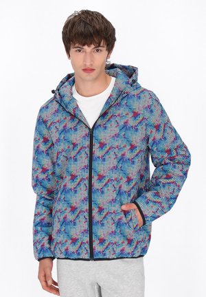 Kapsáč s kapucí s modro-červenobílým geometrickým vzorem, který má přední zip, elastické manžety a boční kapsy.