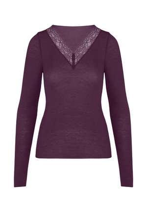 Femme portant un haut violet à manches longues avec un col en V en dentelle et des sous-vêtements assortis, soulevant légèrement l'ourlet pour montrer le ventre.