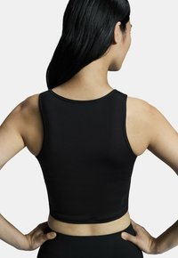 Must lõikega must tank top, mis on valmistatud siledast, venivatest materjalidest. Omab ümarat kaelust ja võidusõidu seljakujundust. Mitte mingit nähtavat graafikat ega mustreid.
