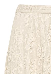 Spetskjol i off-white, med blommönster och en utsvängd design med veck. Slät textur med ett åtsittande midjeband.