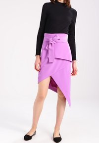 Violetti kietaisuhame epäsymmetrisellä helmalla, sidottu vyötärölle. Valmistettu sileästä kankaasta, siinä on kerrostettu muotoilu ja sivuhalkio.