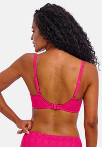 Lyserød blondebralette med justerbare stropper, en hægte lukning og et struktureret diamantmønster. Bagfra afsløres glatte konturer.