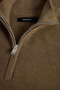 Rudas zip-up megztinis su tekstūruotu raštu, aukštu apykakle ir metaliniu užtrauktuku. Etiketėje parašyta „Matinique“. 
