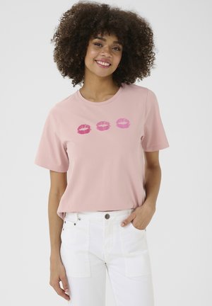 Camiseta de algodón rosa con cuello redondo y mangas cortas, que presenta tres estampados de labios en diferentes tonos de rosa en el pecho.