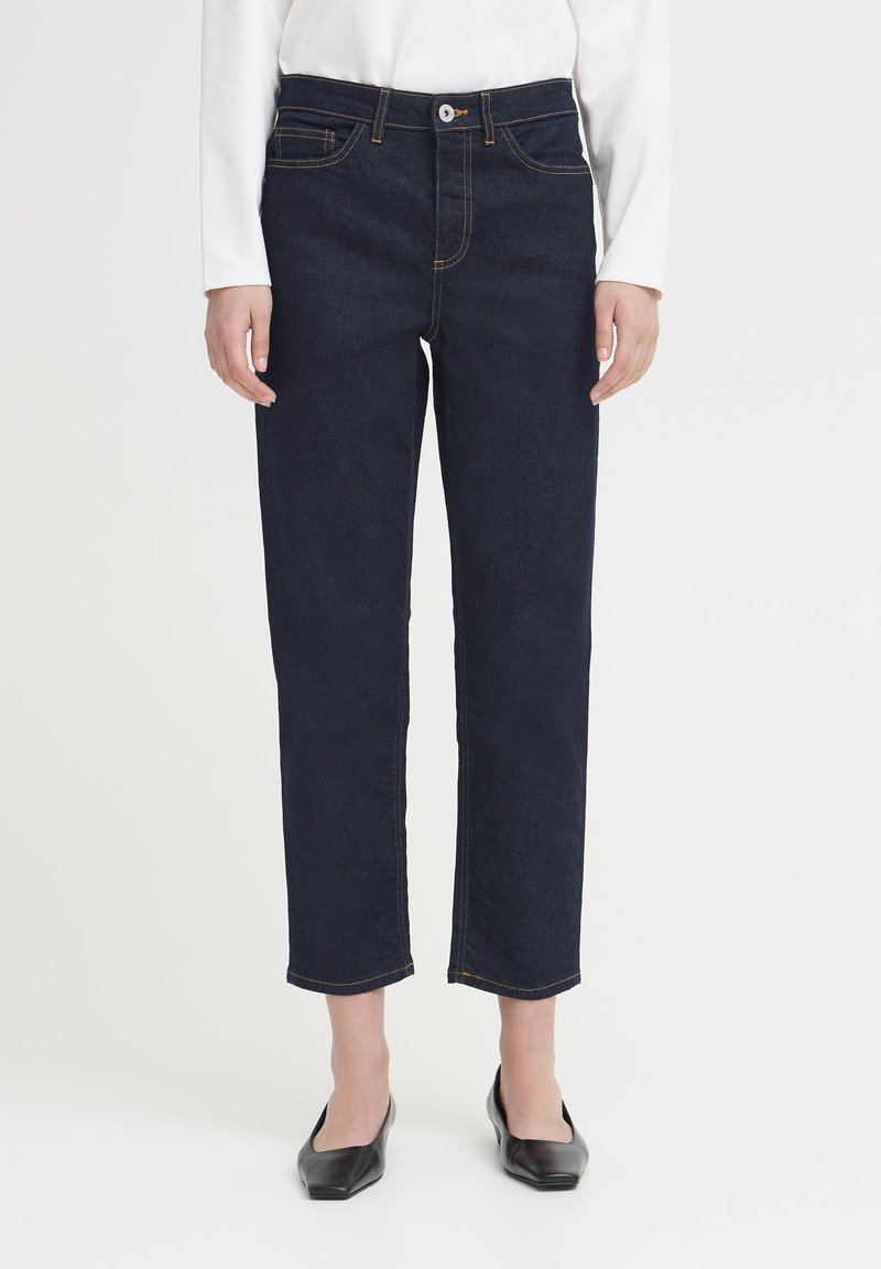 Jean en denim bleu foncé avec une coupe droite, cinq poches, des coutures contrastantes orange et une fermeture par bouton à la taille.