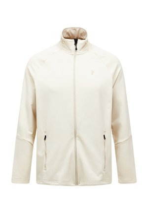 Veste zippée beige clair en tissu doux, avec un col haut, deux poches latérales zippées et un discret logo sur la poitrine.